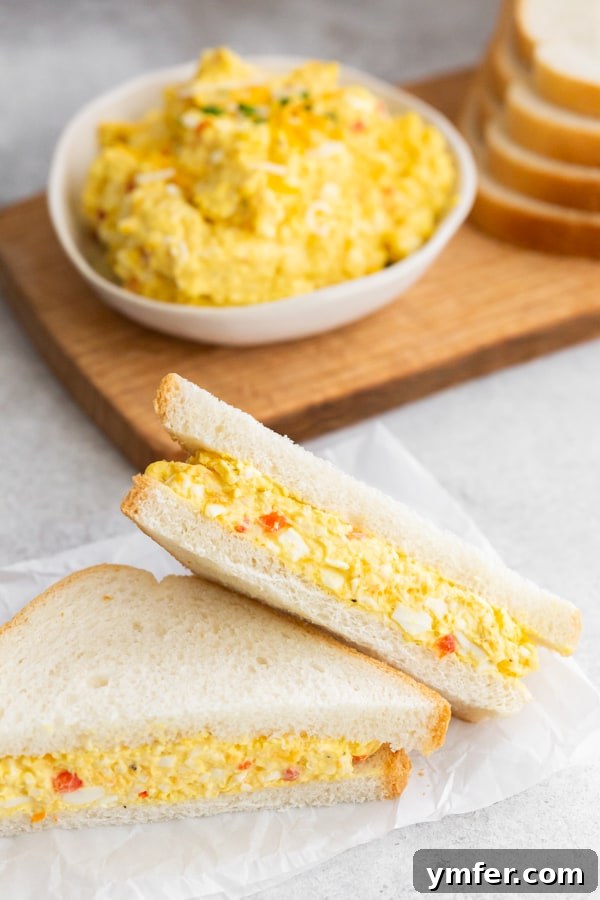 Creamy Pimento and Cheddar Egg Salad 5 Pimento Cheese Egg Salad served on white bread and cut in half.