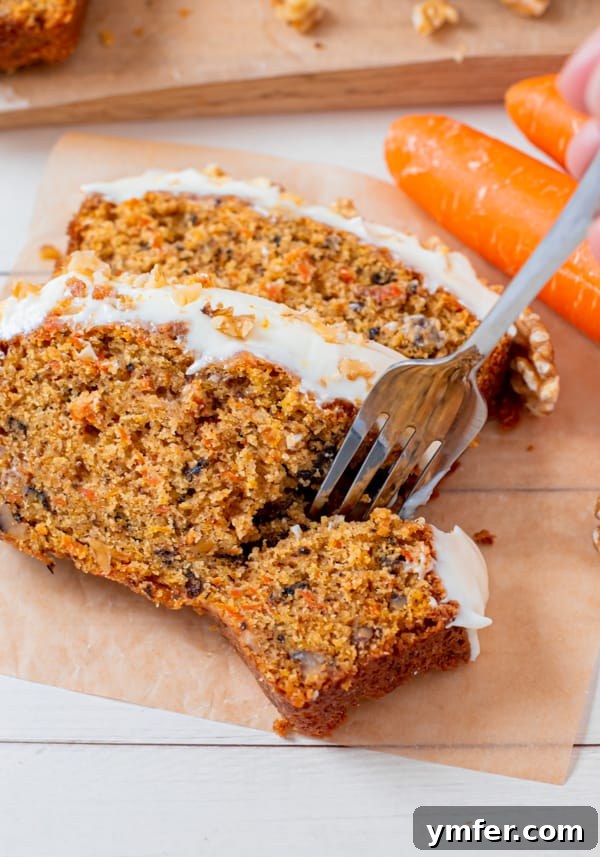 Spiced Carrot Loaf 4 A fork taking a bite of Carrot Cake Loaf Cake, showing the moist interior with visible carrot shreds and nuts.