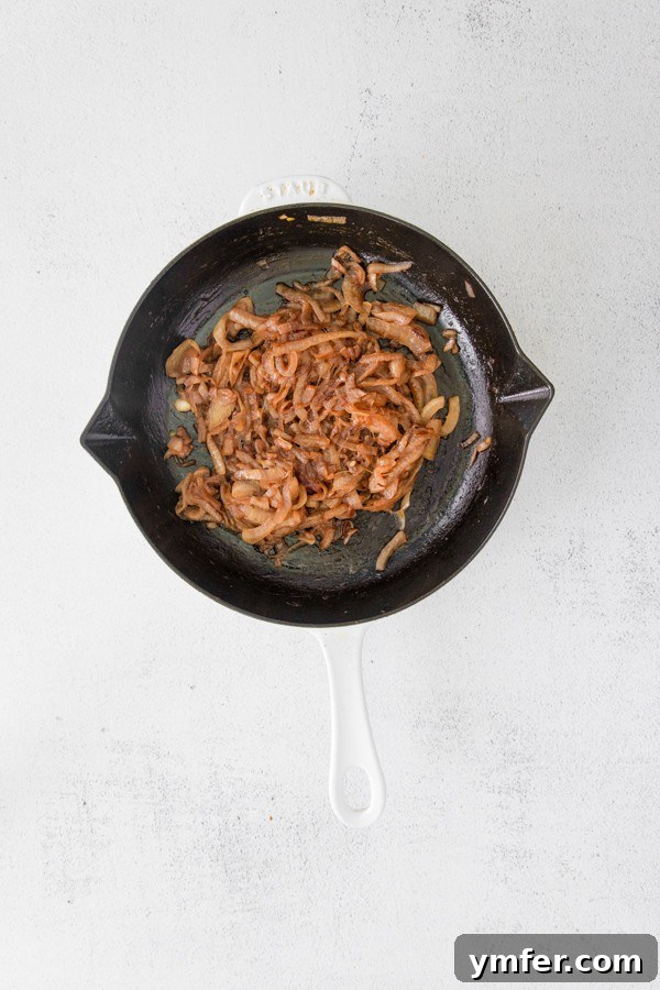 Gourmet Caramelized Onion Dip 3 Thinly sliced sweet onions simmering gently in melted butter in a heavy cast iron skillet, beginning their caramelization journey.