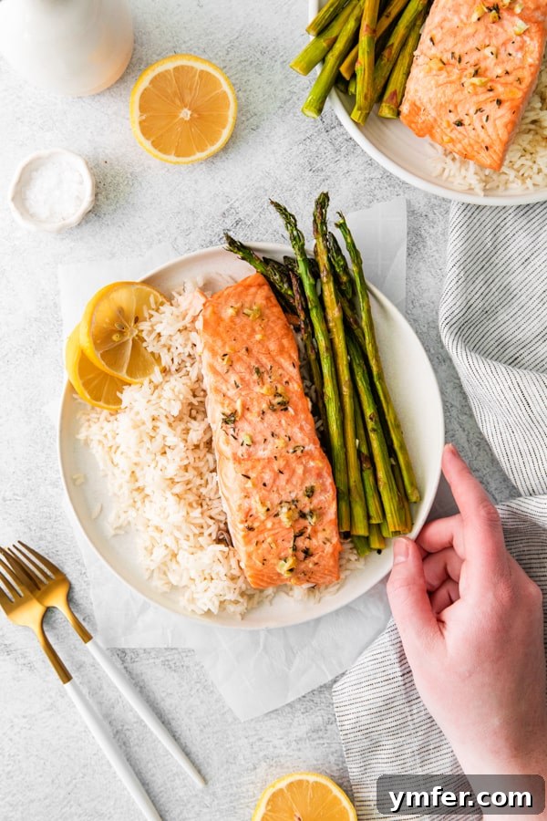 Zesty Lemon Salmon Sheet Pan Dinner 5 A hand holding a served plate of Sheet Pan Lemon Salmon.