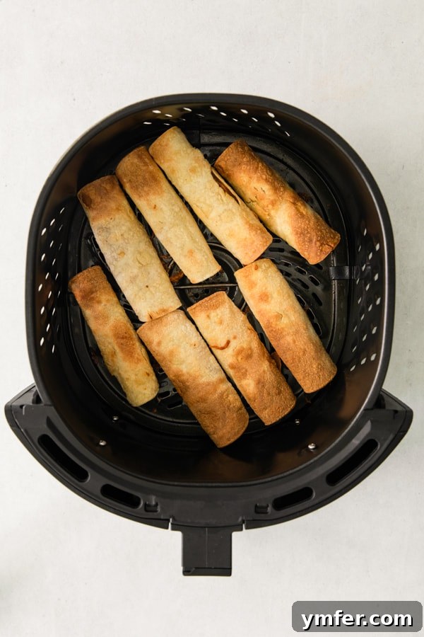 Crispy Air Fryer Chicken Taquitos 4 Air Fryer Chicken Taquitos arranged in the air fryer basket, ready for cooking.