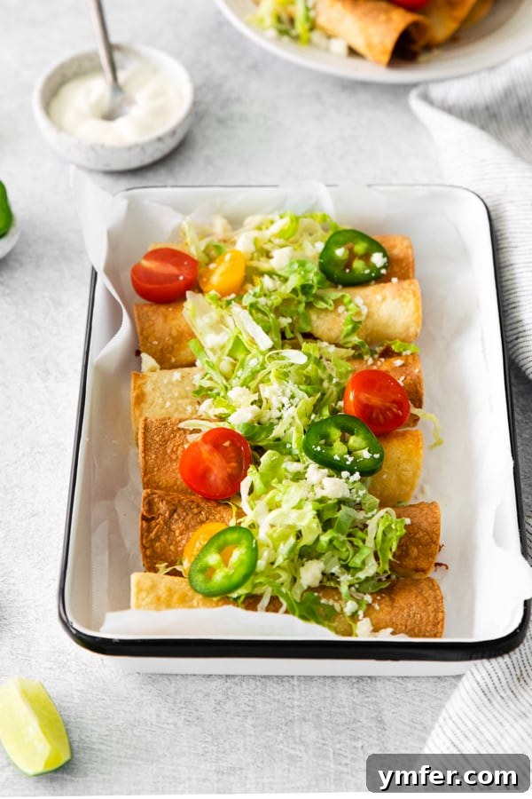 Crispy Air Fryer Chicken Taquitos 5 Air Fryer Chicken Taquitos served on a platter with fresh lettuce and other toppings.