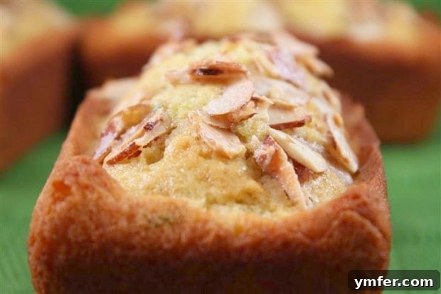 This lime almond coconut oil poundcake is packed full of fresh flavor and is super moist from the use of healthy coconut oil. This is one delicious cake! A close-up of a slice of Lime Pound Cake with visible almonds, showing its moist texture.