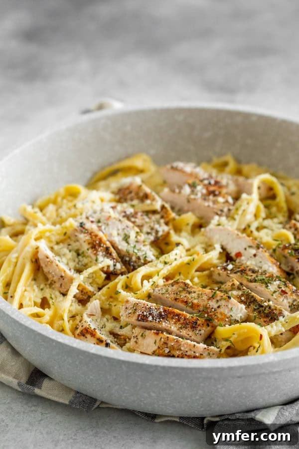 Ultimate Chicken Fettuccine Alfredo 5 Chicken Fettuccine Alfredo in a pan with sliced chicken breast on top of the pasta.
