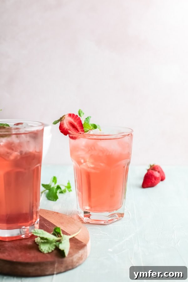 Strawberry Basil Gin Spritzer 6 Two glasses of Strawberry Basil Gin Rickey cocktails, brimming with ice and garnishes, ready to be enjoyed.