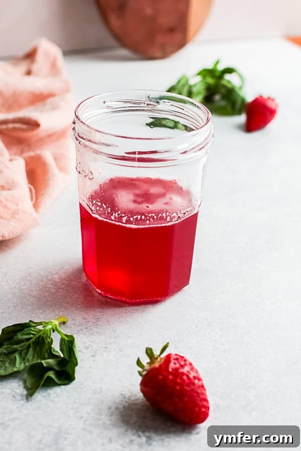 Fresh Strawberry Basil Elixir 7 Close-up view of fresh basil leaves and sliced strawberries simmering in a pot on the stove, infusing flavor into the simple syrup.