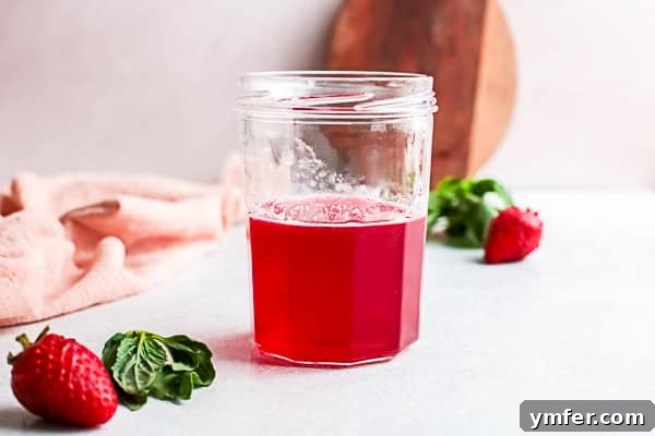 Fresh Strawberry Basil Elixir 8 Collection of various homemade flavored simple syrups in elegant bottles, including a vibrant red strawberry basil syrup.