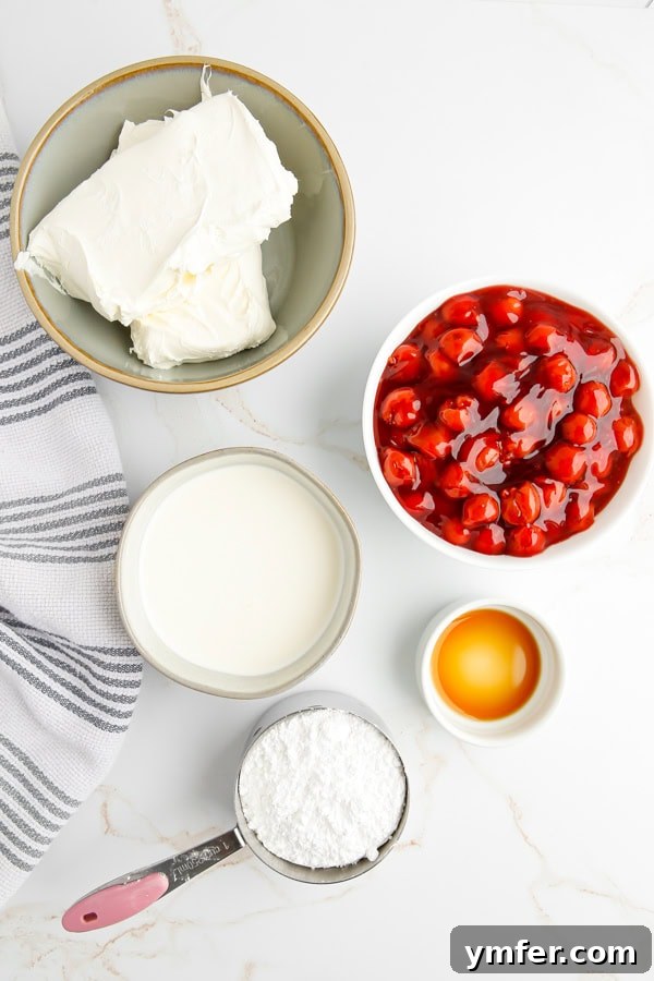 Luscious Cherry Cheesecake Dip 3 All the essential ingredients for making Cherry Cheesecake Dip laid out on a clean kitchen counter, including blocks of cream cheese, a carton of heavy cream, a bag of powdered sugar, a bottle of vanilla extract, and a can of cherry pie filling.