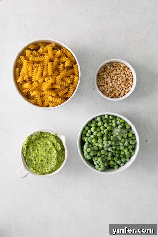 Vibrant Pesto Pasta Salad 3 Fresh ingredients for Pesto Pasta Salad neatly arranged on a rustic wooden table.