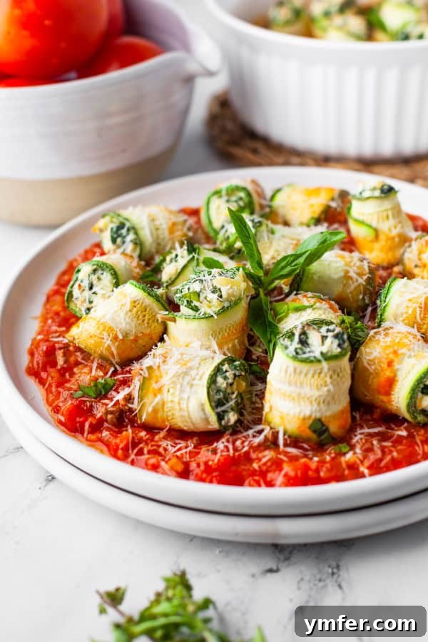 Zucchini Lasagna Rolls on a plate with extra red sauce. 