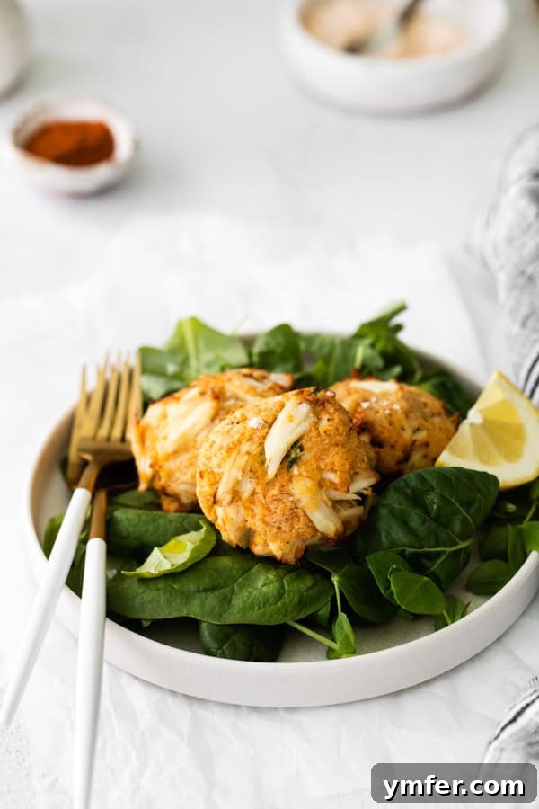 Crispy Air-Fried Crab Cakes 5 Delicious Air Fryer Crab Cakes plated with a fresh mixed greens salad and a lemon wedge.