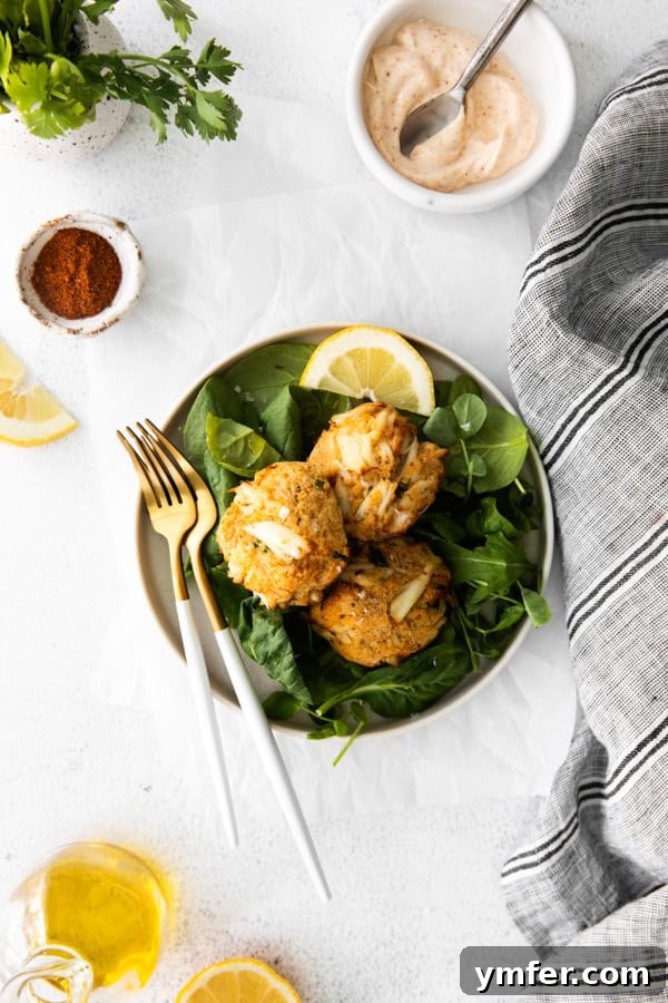 Crispy Air-Fried Crab Cakes 6 A single Air Fryer Crab Cake presented on a white plate with a fork and a squeeze of fresh lemon.