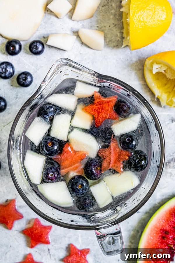 Nation's Nectar 4 Patriotic Lemonade in a clear glass pitcher, with fruit settled at the bottom.