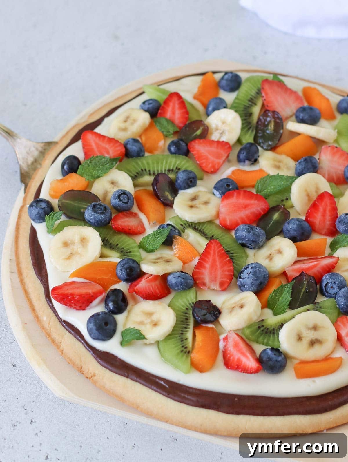 Rainbow Fruit Pizza 11 A beautifully arranged fruit pizza, topped with an assortment of colorful fresh fruits like strawberries, blueberries, kiwi, and grapes, ready to be served.