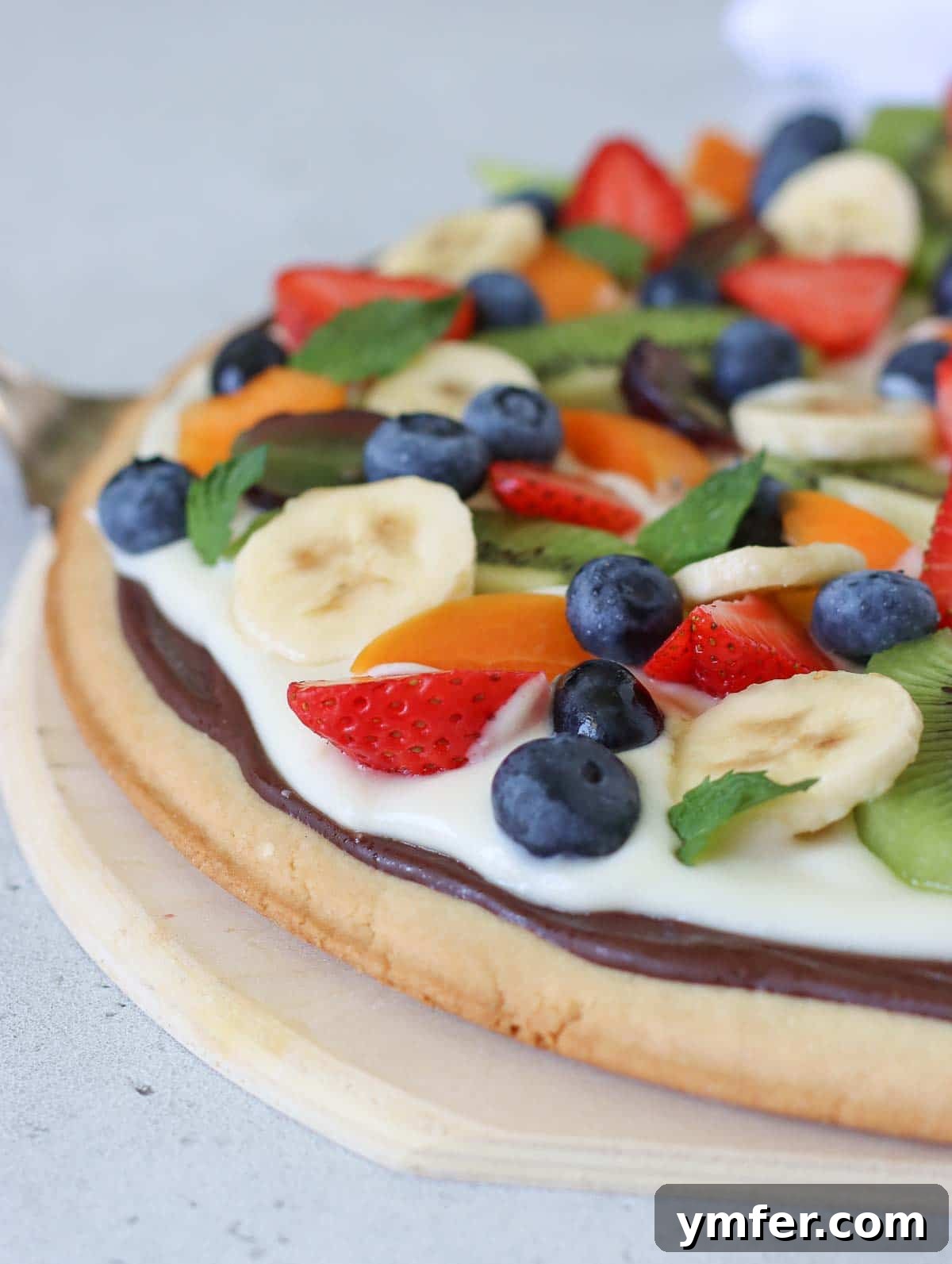 Rainbow Fruit Pizza 12 Close-up of a fruit pizza base, showing the crunchy cookie crust, a rich chocolate layer, and a smooth cream cheese topping, demonstrating texture and structure.