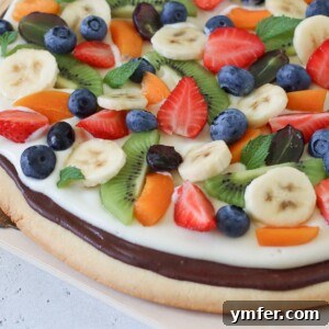 Rainbow Fruit Pizza 16 A beautifully garnished fruit pizza with a variety of colorful fruits, presented on a round platter, ready for serving.