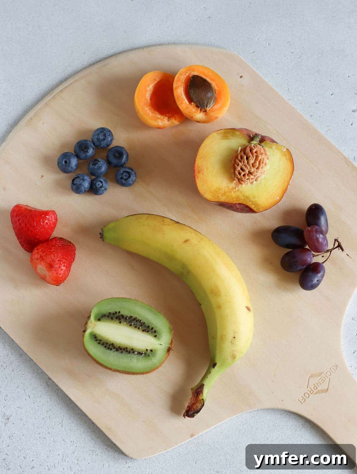 Rainbow Fruit Pizza 5 A vibrant selection of fresh, colorful fruits including strawberries, blueberries, kiwi, and grapes, ready to top a delicious fruit pizza.