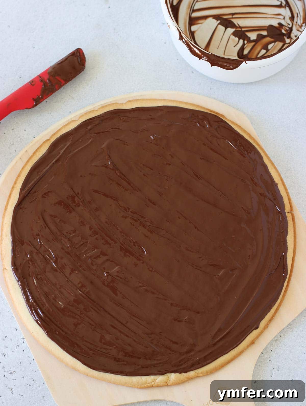 Rainbow Fruit Pizza 9 A perfectly baked sugar cookie crust evenly coated with a thin, glossy layer of melted dark chocolate, ready for the next topping.