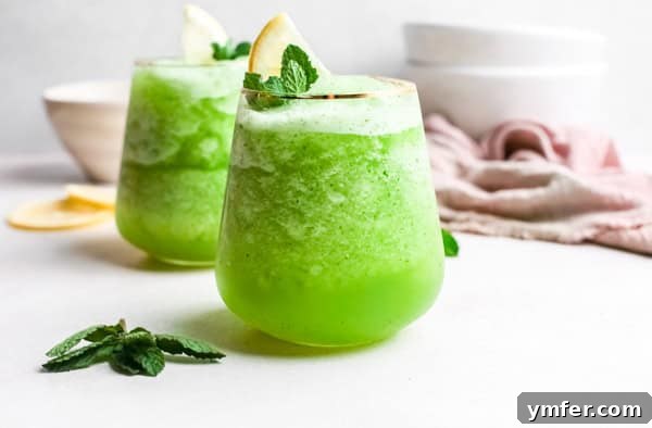 Limonana Frost 6 Several small cocktail glasses filled with frozen mint lemonade, garnished with small mint leaves, on a light surface.