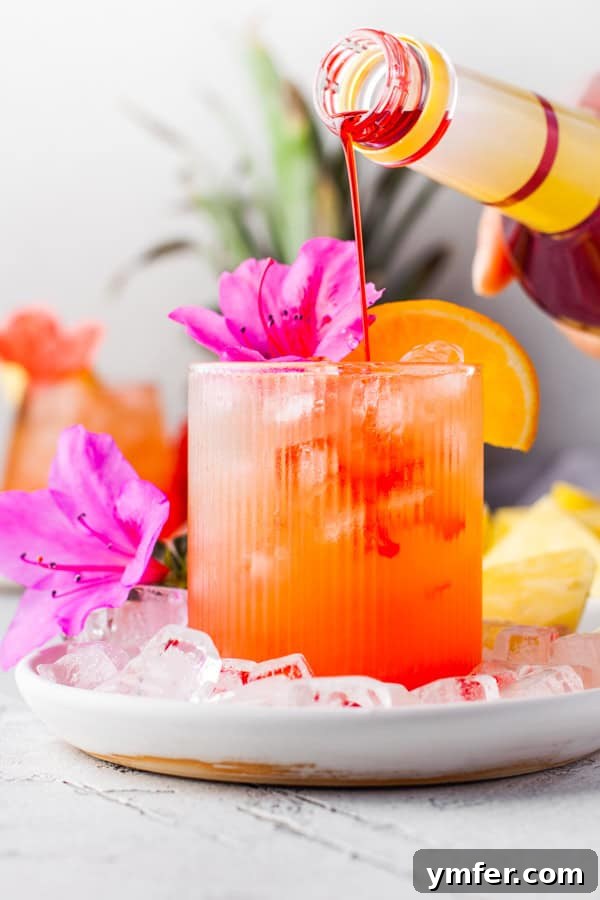 Tropical Rum Delight 5 Pineapple Rum Punch having grenadine poured into the cocktail.