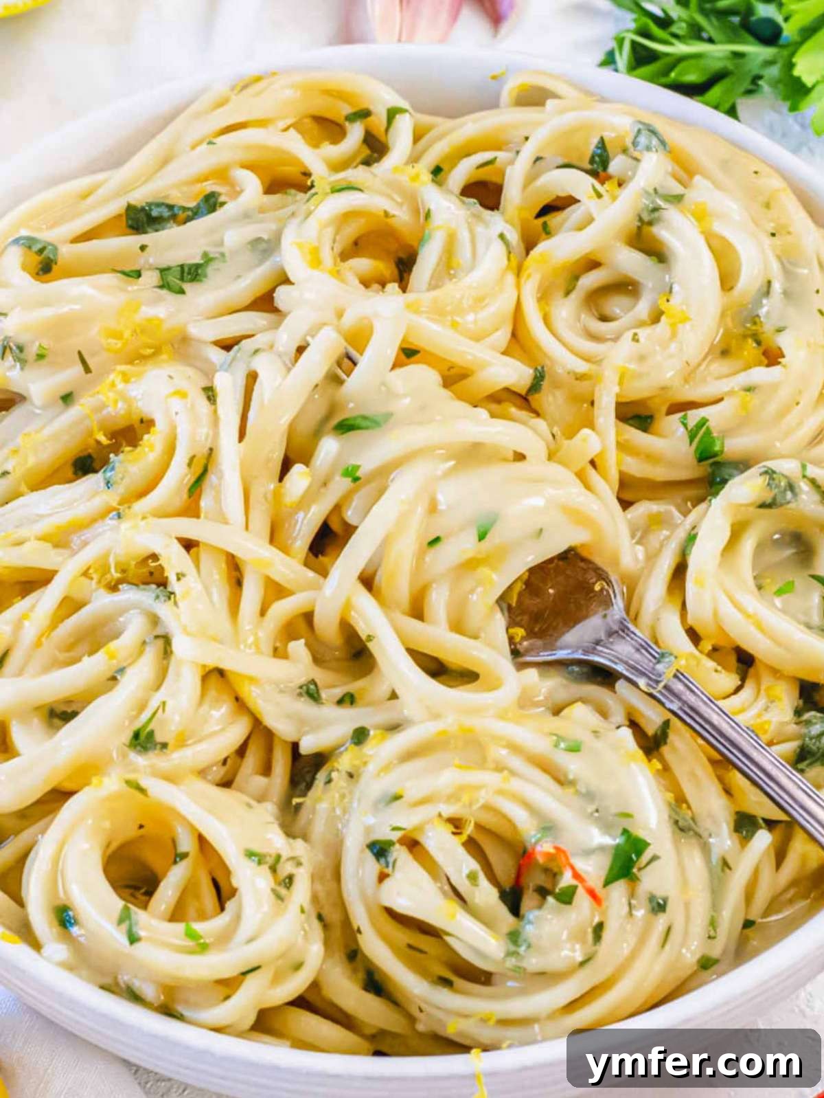 Effortless Lemon Pasta (Creamless) 2 Close-up of lemon pasta without cream, twirled on a fork and garnished with fresh parsley and lemon zest.