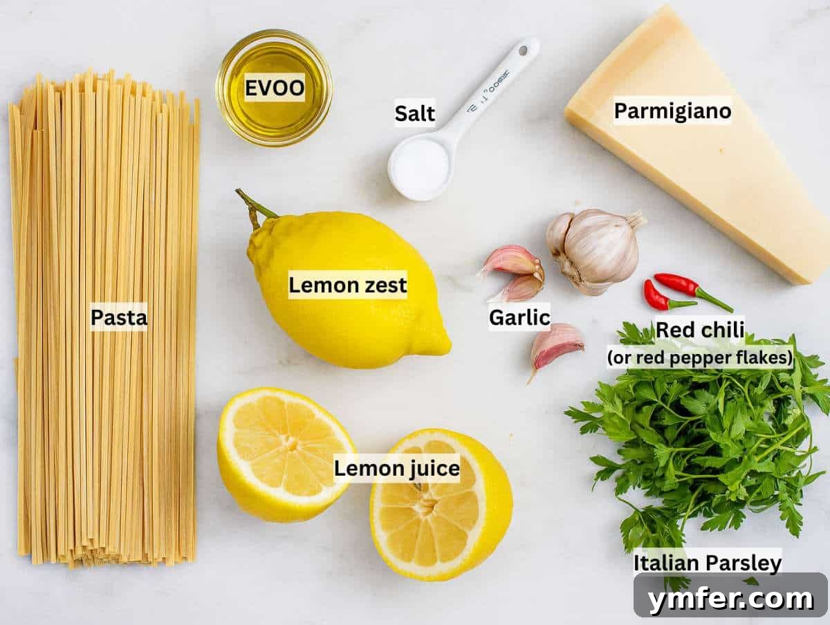Effortless Lemon Pasta (Creamless) 4 Flat lay of ingredients for lemon pasta without cream, including spaghetti, garlic, lemon, olive oil, parsley, chili, and parmesan cheese.