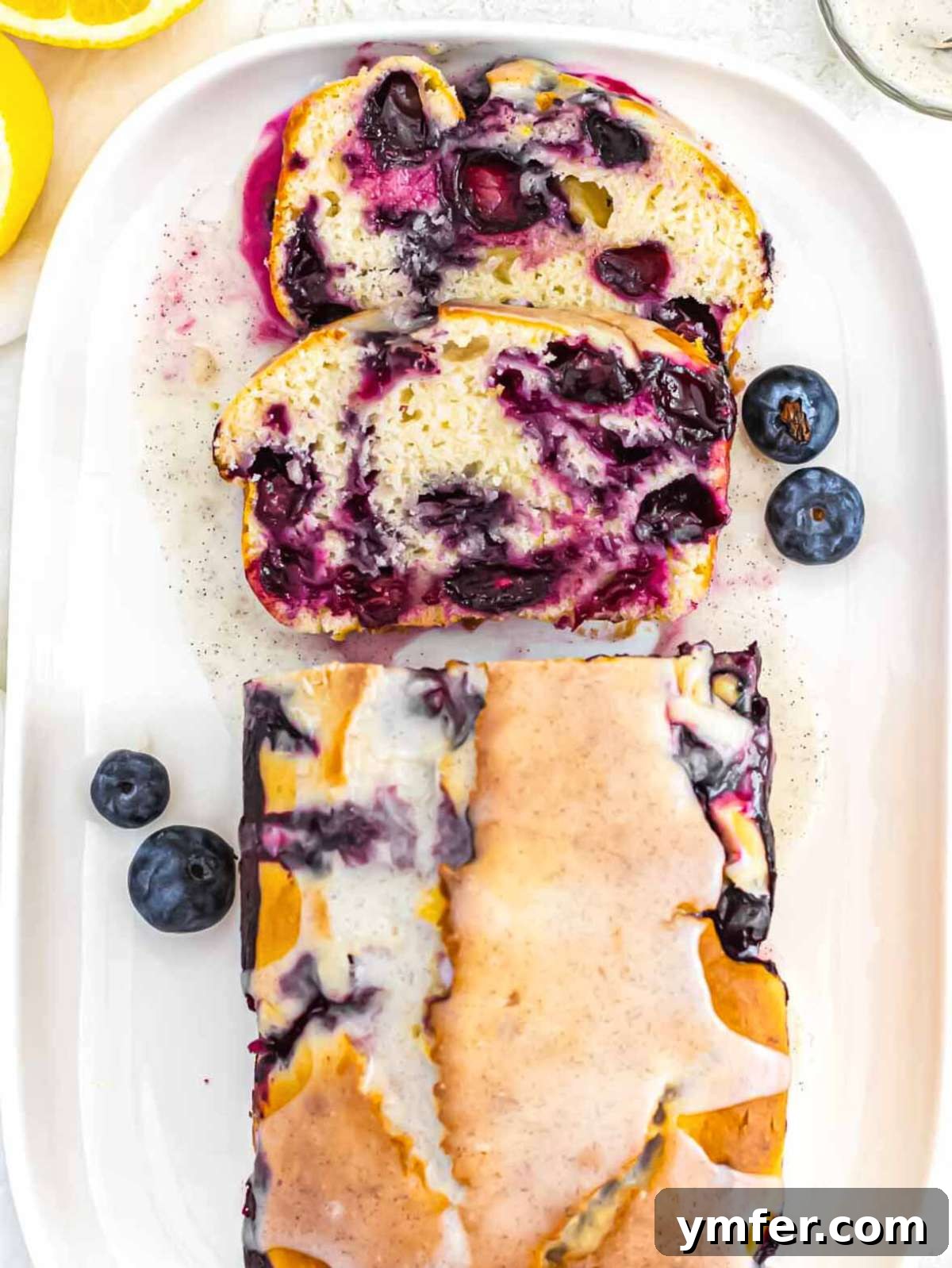 Lush Blueberry Pound Cake 8 Baked blueberry pound cake covered with a bright lemon glaze, ready for slicing.