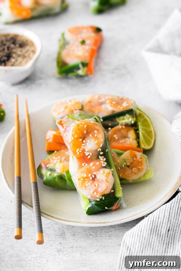 Refreshing Shrimp Garden Rolls 4 Close-up of three beautifully rolled Shrimp Summer Rolls, lightly sprinkled with sesame seeds, served on a white plate ready for dipping.