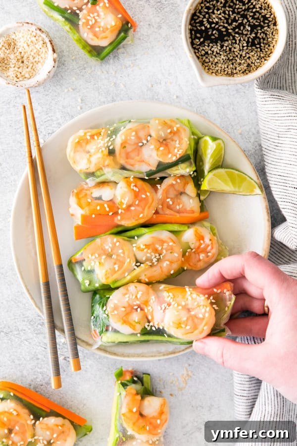 Refreshing Shrimp Garden Rolls 6 A hand reaching for a single, perfectly crafted Shrimp Summer Roll, highlighting its deliciousness and inviting nature.