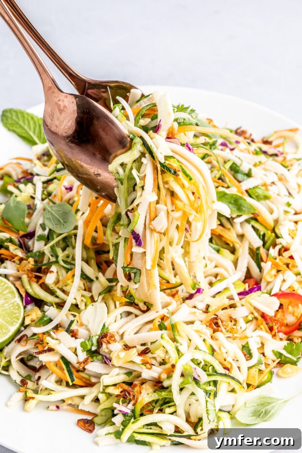 Zesty Vietnamese Zoodle Bowl 5 Vietnamese Zoodle Noodle Salad being served with salad tongs, highlighting its fresh appeal.