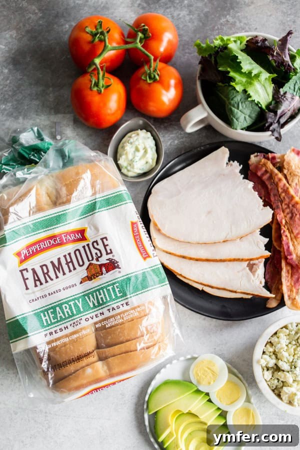The Ultimate Cobb Sandwich 3 Ingredients laid out for a Cobb Salad Sandwich, including bread, chicken, bacon, eggs, avocado, and fresh vegetables.