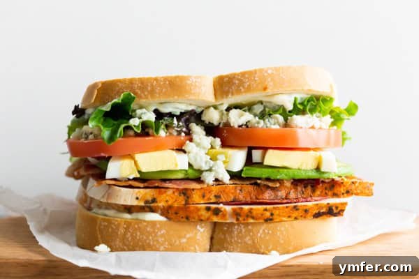 The Ultimate Cobb Sandwich 6 A beautifully presented Cobb Salad Sandwich on parchment paper, ready to be enjoyed.