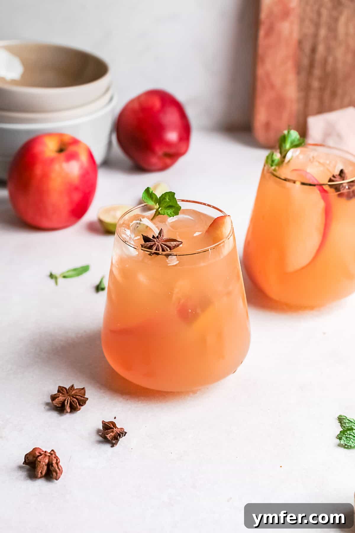 Two glasses of Apple Cider Mojito, garnished with mint and lime, sitting on a table, ready to be enjoyed.