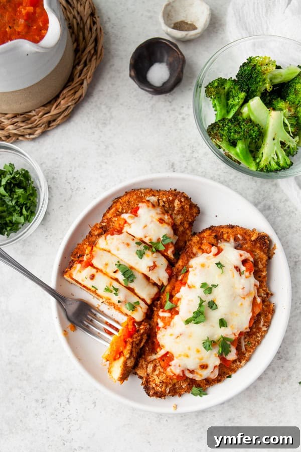 Crispy Air Fryer Chicken Parmesan 2 Crispy Air Fryer Chicken Parmesan on a white plate with a fork, ready to be enjoyed.