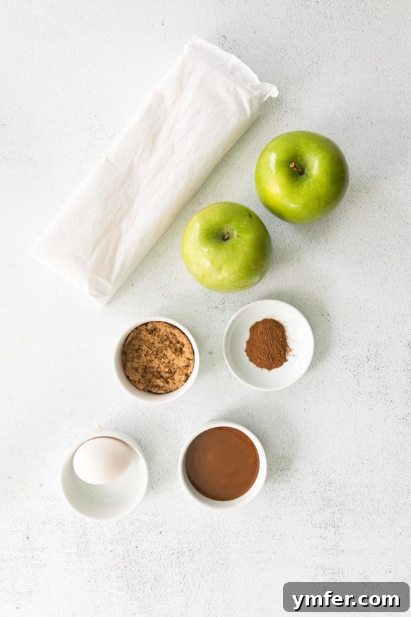 Gooey Apple Caramel Pastry 3 A vibrant flat lay of essential ingredients: thawed puff pastry, sliced Granny Smith apples, brown sugar, and cinnamon, arranged on a textured surface.