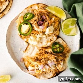 Effortless Instant Pot Chicken Tacos 13 A finished Instant Pot Shredded Chicken Taco, garnished with fresh toppings, on a white plate.