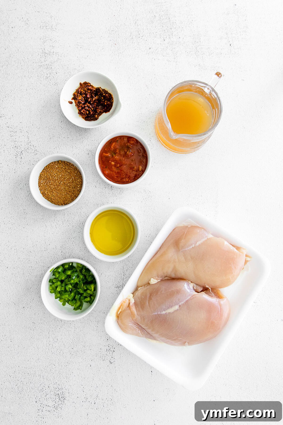 Effortless Instant Pot Chicken Tacos 3 A collection of fresh ingredients for Instant Pot Chicken Tacos displayed on a rustic wooden table, including chicken breasts, jars of salsa and chipotles in adobo, olive oil, and seasoning.