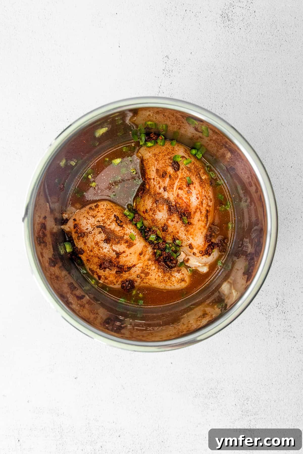 Effortless Instant Pot Chicken Tacos 4 Raw uncooked chicken with spices and salsa ready to be pressure cooked in an Instant Pot pot.