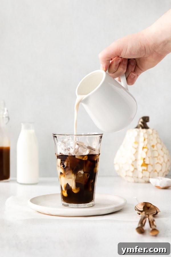 Pouring milk into a glass of Iced Pumpkin Chai Latte. 