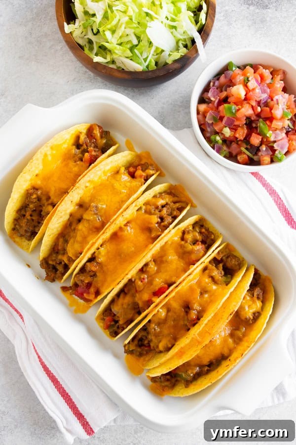 Crispy Baked Beef Tacos 3 Baked Ground Beef Tacos covered in rich, melted cheese, ready to be topped and served.