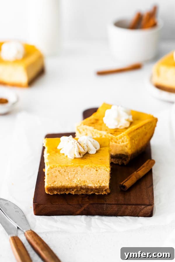 Autumn Pumpkin Cheesecake Squares 4 Cut pumpkin cheesecake bars topped with whipped cream.