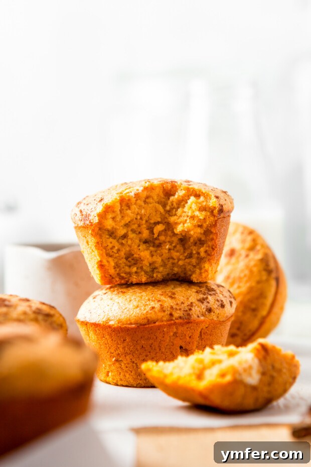 Golden Spiced Pumpkin Cornbread Muffins 6 Multiple Sweet Pumpkin Cornbread Muffins stacked elegantly, showcasing their golden-brown tops and inviting texture.