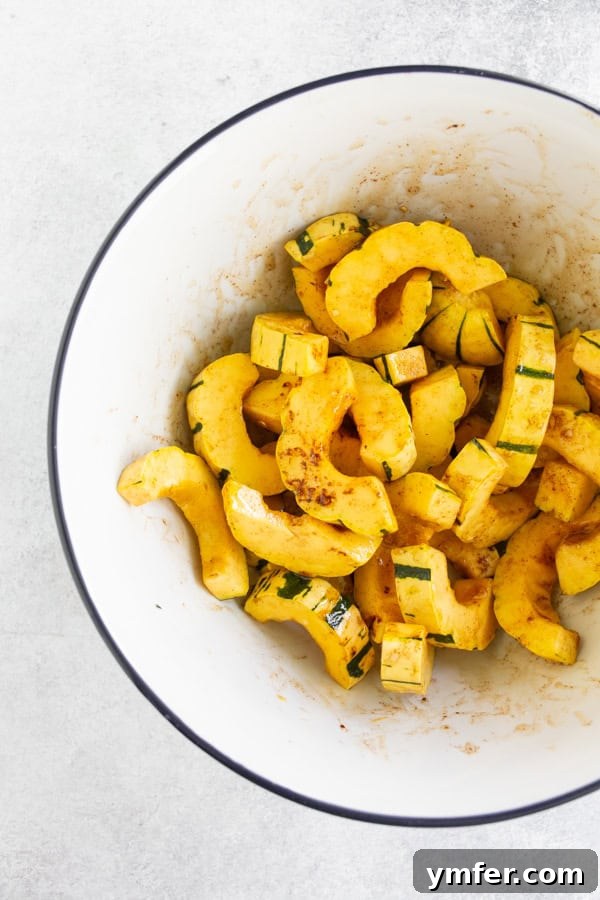 Maple Cinnamon Delicata Jewels 3 Sliced delicata squash in a bowl mixed with ingredients before roasting, showing even coating.