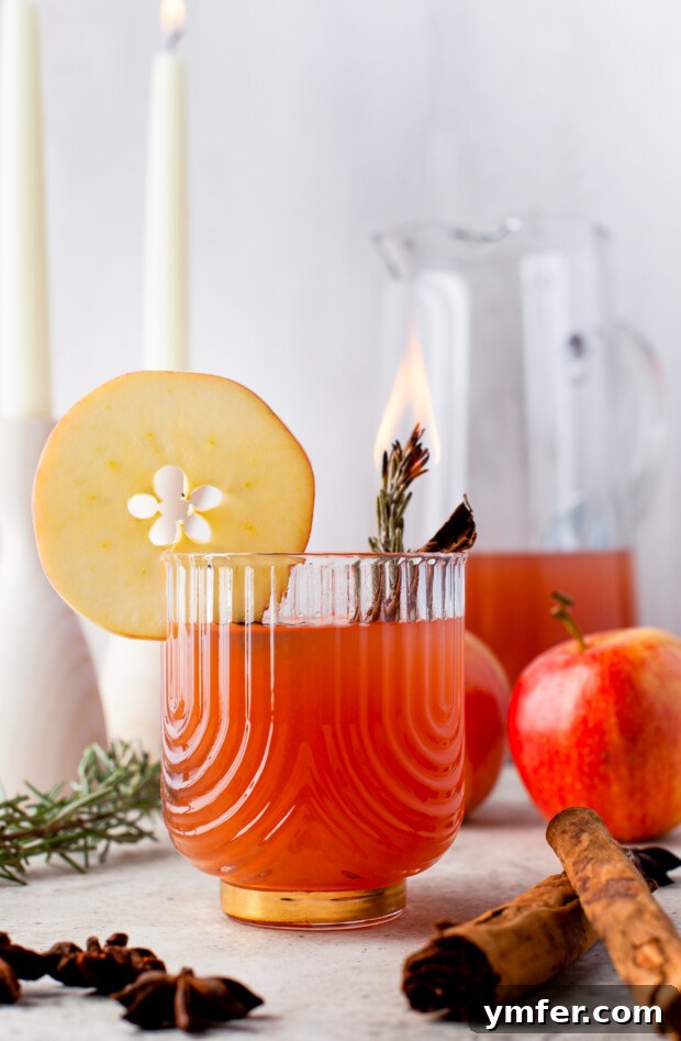 Instant Pot Spiced Apple Cider 7 Instant Pot Apple Cider in a glass garnished with flaming rosemary, creating a dramatic effect.