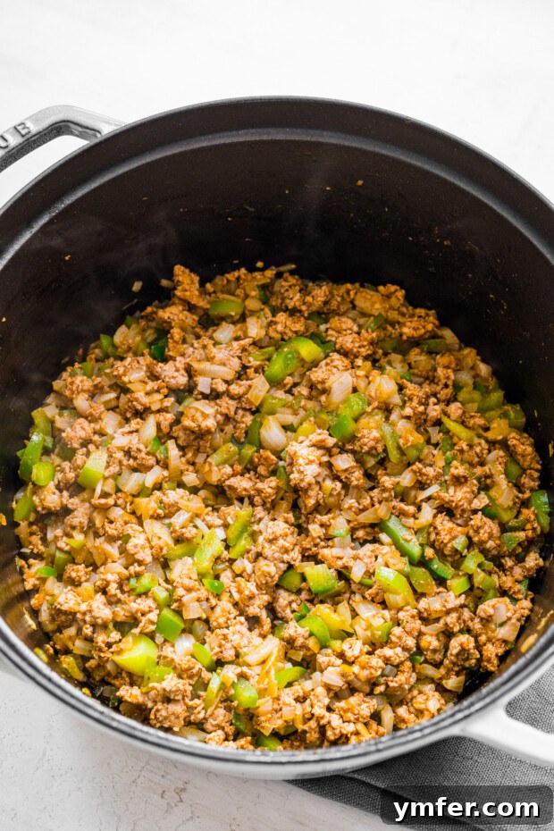 Autumn Harvest Turkey Chili 4 Sautéed ground turkey and a colorful mix of diced onions, bell peppers, and jalapeños sizzling in a large soup pot, releasing aromatic steam as they cook.