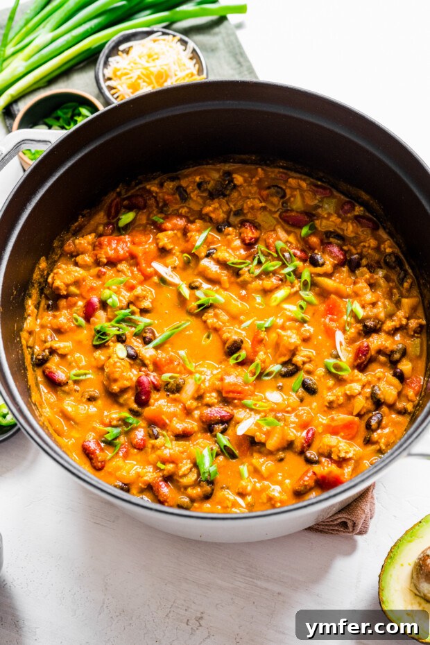 Autumn Harvest Turkey Chili 6 A large, rustic soup pot brimming with fully cooked Turkey Pumpkin Chili, its rich, deep color and inviting texture promising a satisfying and flavorful meal.