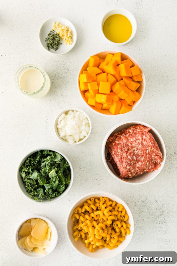 Autumn Butternut Squash Sausage Pasta 3 All the fresh ingredients for Butternut Squash Sausage Pasta, including raw squash, kale, and sausage, laid out on a kitchen counter.