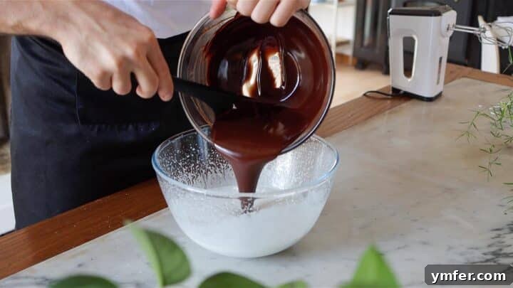 Decadent Chocolate Brownie Cake 12 Pouring melted chocolate into the aerated aquafaba and sugar mixture to create the brownie batter