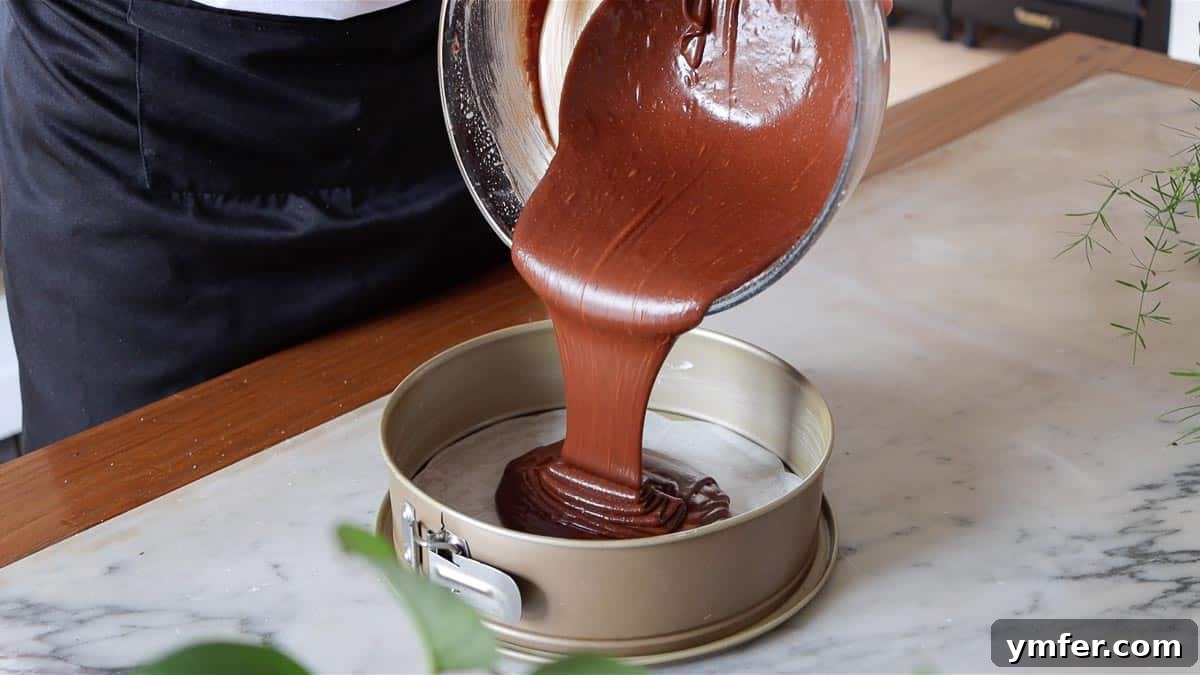 Decadent Chocolate Brownie Cake 16 Pouring the smooth chocolate brownie cake batter into a parchment-lined springform pan before baking