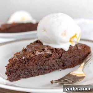 A slice of vegan chocolate brownie cake with a scoop of vegan vanilla ice cream on top